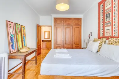 a bedroom with a white bed and a table at OPORTO GUEST Lobo Flat with Parking in Porto