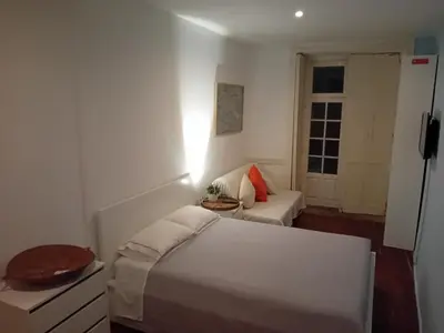 a white bedroom with a bed and a window at Oupas 2 Lofts in Porto
