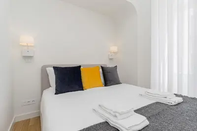 a white bed with colorful pillows on top of it at Charming Apartment • Porto in Porto