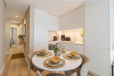 a kitchen and dining room with a white table and chairs at T2 Constituição in Porto