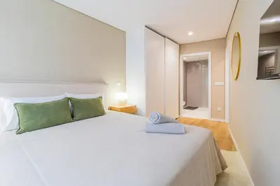 a bedroom with a large white bed with green pillows at T2 Constituição in Porto