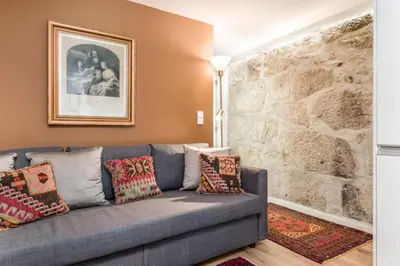 a couch in a living room with a stone wall at Cute 1-bedroom next to Douro River in Porto