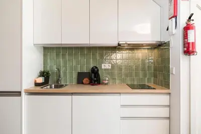 a kitchen with white cabinets and green tiles at Cute 1-bedroom next to Douro River in Porto