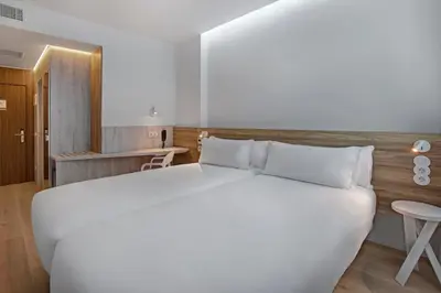 a bedroom with a large white bed and a table at B&B HOTEL Porto Gaia in Vila Nova de Gaia