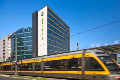 a yellow train in front of a tall building at B&B HOTEL Porto Gaia in Vila Nova de Gaia