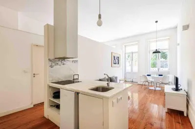 a white kitchen with a sink and a dining room at Santa Catarina Studio Apartments in Porto