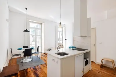 a kitchen with white cabinets and a table with chairs at Santa Catarina Studio Apartments in Porto