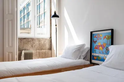a bedroom with two beds with white sheets and a window at Santa Catarina Studio Apartments in Porto