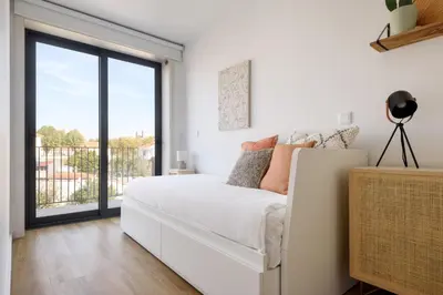 a white bedroom with a bed and a large window at Lovely 2-bed in the city centre with a sunny balcony in Porto