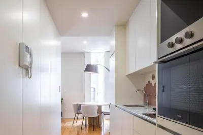 a kitchen with white cabinets and a table with chairs at Formosa Studio with Balcony by LovelyStay in Porto