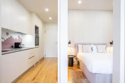 a white bedroom with a bed and a kitchen at Formosa Studio with Balcony by LovelyStay in Porto