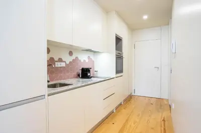 a kitchen with white cabinets and a wooden floor at Formosa Studio with Balcony by LovelyStay in Porto