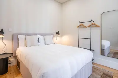 a bedroom with a large white bed and a mirror at Formosa Studio with Balcony by LovelyStay in Porto