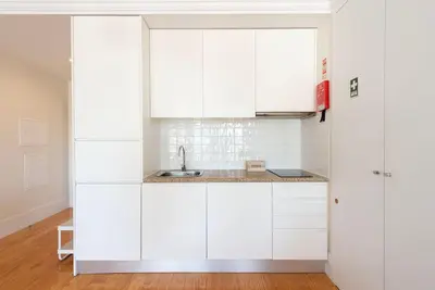 a kitchen with white cabinets and a sink at Cedofeita Studio - Your Porto Escape in Porto