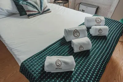 a bedroom with a white bed with two green stools at Mira Alfandega apartment in Porto