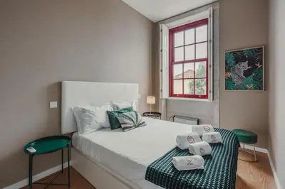 a kitchen with white cabinets and a couch in a room at Mira Alfandega apartment in Porto