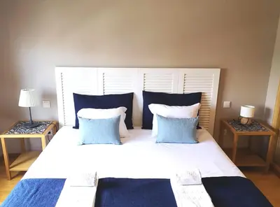 a bedroom with a large white bed with blue pillows at Palácio Garden's House by LovelyStay in Porto