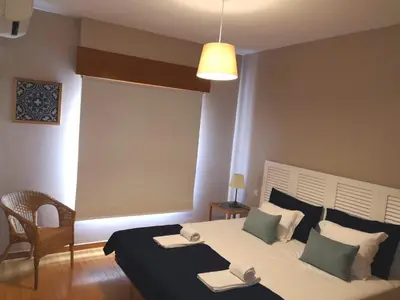 a bedroom with a large bed and a chair at Palácio Garden's House by LovelyStay in Porto