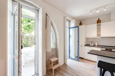 a kitchen with white cabinets and a large window at VIVA Boavista Vintage House in Porto