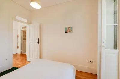 a white bedroom with a white bed and a door at VIVA Boavista Vintage House in Porto