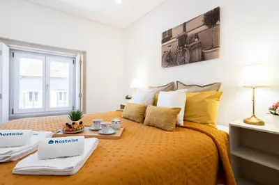 a bedroom with a bed with a orange bedspread at Host Wise - Modern Urban Flat in Porto