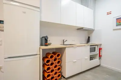 a kitchen with white cabinets and a shelf with wooden logs at Green Hideaway by LovelyStay in Porto