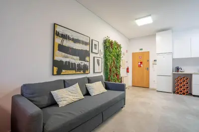 a living room with a gray couch and a kitchen at Green Hideaway by LovelyStay in Porto