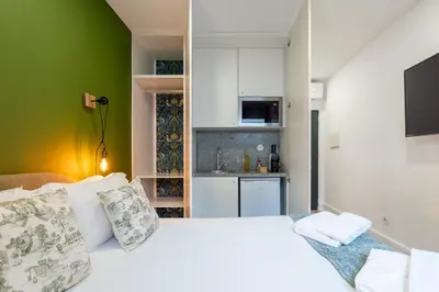 a bedroom with a white bed and a kitchen at Casa D'Almeida by Porto Stories in Porto