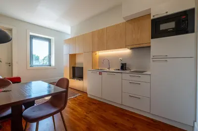 a kitchen with white cabinets and a dining table at HM - Oporto Studio Pool Oasis in Porto