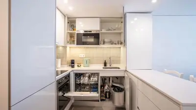 a small kitchen with white cabinets and a dishwasher at Serene 1BR Spot by LovelyStay in Porto