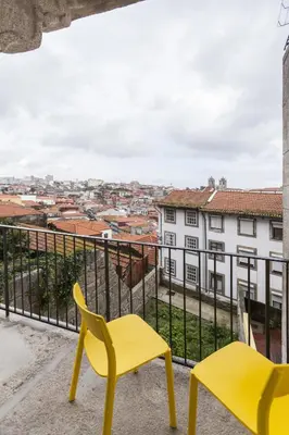a balcony with yellow chairs and a view of a city at Merc Porto Vitoria's Place in Porto