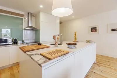 a kitchen with white cabinets and a counter top at Merc Porto Vitoria's Place in Porto