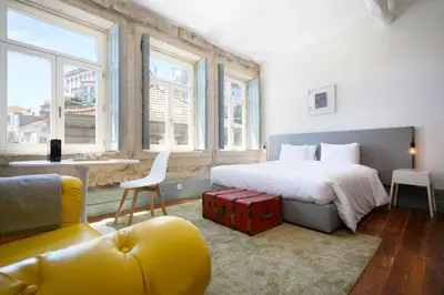 a bedroom with a bed and a couch and windows at Live In Porto - Codeçal in Porto