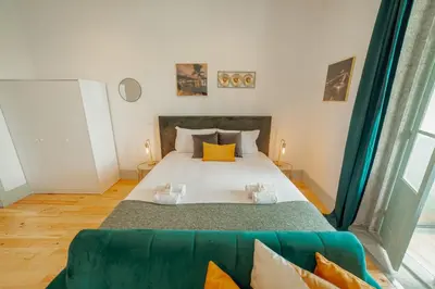 a bedroom with a large bed and a green couch at Downtown Suites by Vacationy in Porto