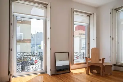 a room with three windows and a table and a chair at Casa B in Porto