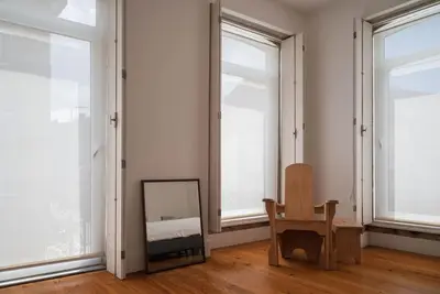 a room with a mirror and a chair and windows at Casa B in Porto
