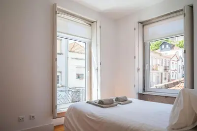a bedroom with a bed and two large windows at Casa B in Porto