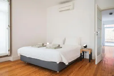 a white bedroom with a large bed and a wooden floor at Casa B in Porto