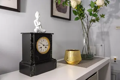 a clock sitting on top of a table with flowers at Refugio no oPorto in Porto