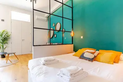 a bedroom with a large white bed with a green wall at Modern Downtown Studio in Porto