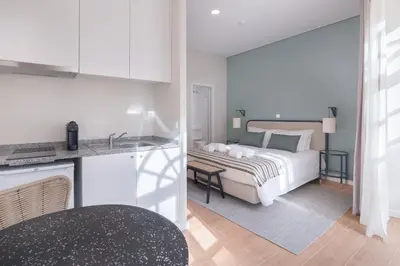 a white bedroom with a bed and a kitchen at VC Heritage Ribeira Porto in Porto