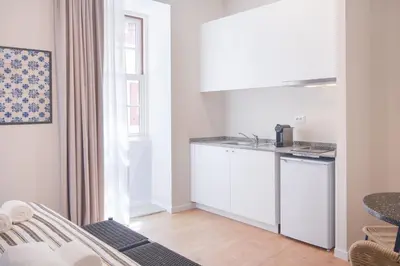 a kitchen with white cabinets and a window at VC Heritage Ribeira Porto in Porto
