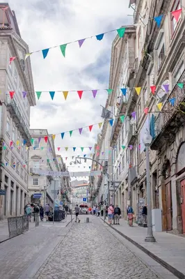 a street with flags and people walking down the street at VC Heritage Ribeira Porto in Porto
