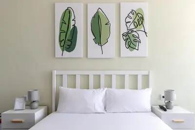 three prints of leaves on the wall above a bed at Porto Riverville Apartments in Porto