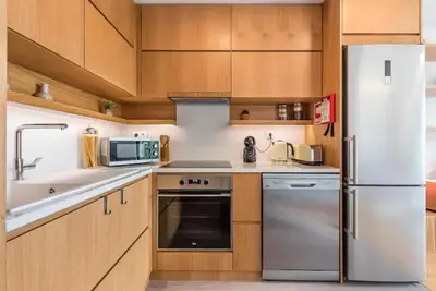 a kitchen with a white refrigerator and wooden cabinets at ApartmentsPorto - Leisure Fun Apartment in Porto
