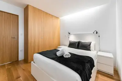 a bedroom with a large white bed and wooden cabinets at ApartmentsPorto - Leisure Fun Apartment in Porto