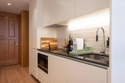 a kitchen with white cabinets and a black counter top at PortoPoint in Porto