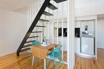 a kitchen and dining room with a table and blue chairs at GuestReady - Climbing Loft in Porto