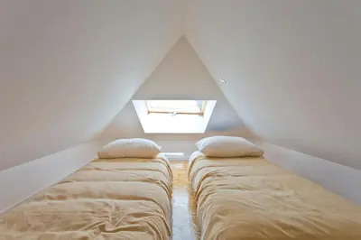 two beds in a attic room with a window at GuestReady - Climbing Loft in Porto