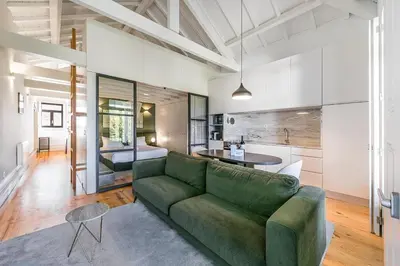 a living room with a green couch and a kitchen at GuestReady - Loft 515 in Porto